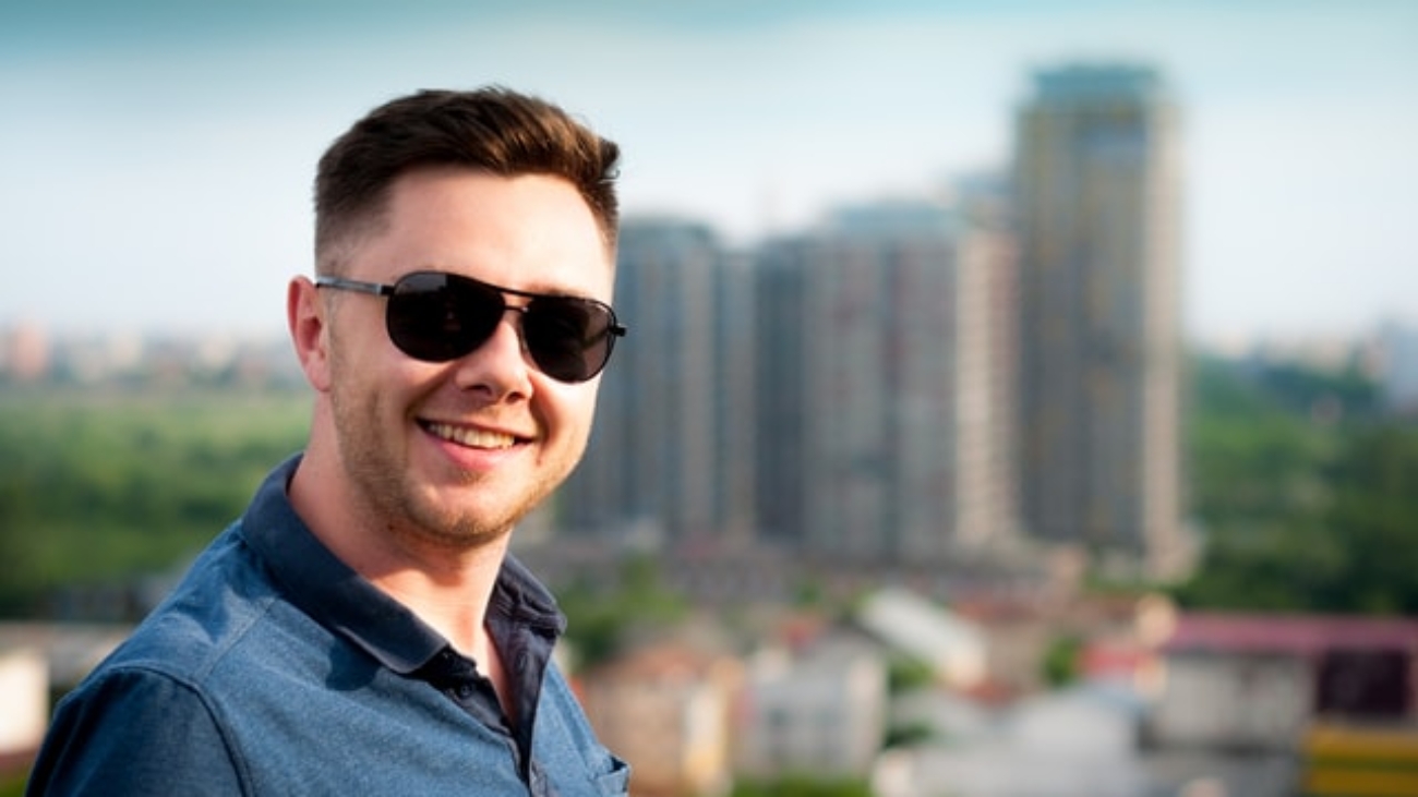 man smiling with buildings in background